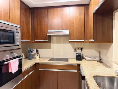 a kitchen with wooden cabinets and a microwave at Stylish 1BHK in Marina Steps to Metro & Marina Walk in Dubai