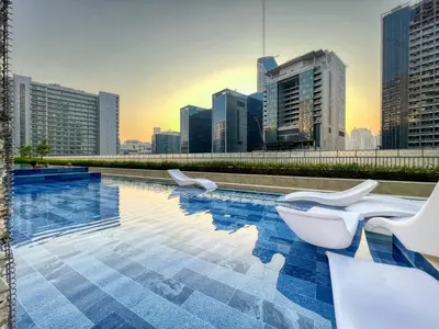 a swimming pool with white chairs and a city skyline at 1BR Apartment with Canal View near Dubai Mall & Burj Khalifa in Dubai
