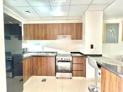a kitchen with wooden cabinets and a stainless steel stove at 3 BR Fully Furnished with BBQ Griller in Dubai