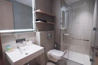 a bathroom with a toilet and a sink and a shower at Chic 2BR in Oakley Square Residence, JVC in Dubai