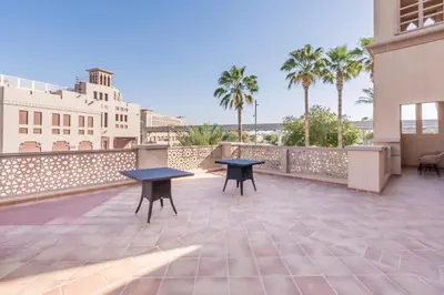 two tables on the roof of a building with palm trees at Near the Beach 4BR Villa with Assistant's Room, Minutes Away from the Mall and Monorail, Canal Cove, Palm Jumeirah by Deluxe Holiday Homes in Dubai