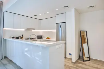 a white kitchen with a sink and a counter at Bright and Modern City Apartment in Business Bay with Two Balconies, Pool, Gym, free Parking and Self Check In, Sleeps up to Four, by Stayfinity in Dubai