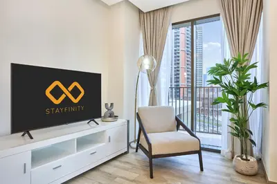 a living room with a tv and a chair at Bright and Modern City Apartment in Business Bay with Two Balconies, Pool, Gym, free Parking and Self Check In, Sleeps up to Four, by Stayfinity in Dubai