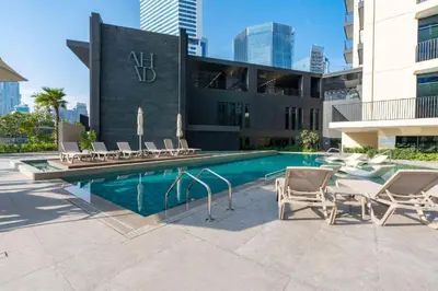 a swimming pool with chairs and a building at Bright and Modern City Apartment in Business Bay with Two Balconies, Pool, Gym, free Parking and Self Check In, Sleeps up to Four, by Stayfinity in Dubai