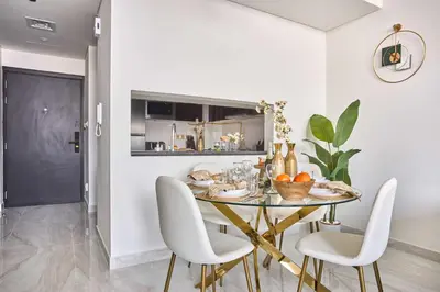 a dining room with a glass table and white chairs at Frank Porter - Gemz by Danube in Dubai
