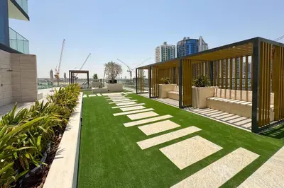 a garden with green grass and a building at Exclusive 1 Bedroom in Trillionaire Residences in Dubai