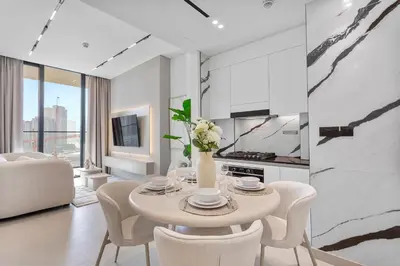 a white dining room with a table and chairs at Exclusive 1 Bedroom in Trillionaire Residences in Dubai