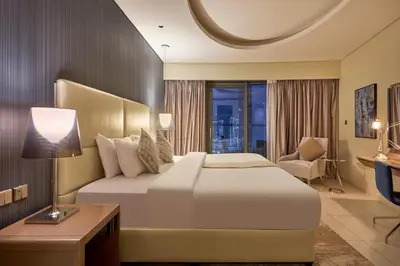 a hotel room with a large bed and a chair at Spacious 2 Bedroom Apartment in DAMAC Towers by Paramount Dubai with Pool Gym Free Parking Sleeps 4 by Stayfinity in Dubai