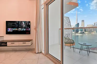 a living room with a tv and a large window at Stylish Escape with Balcony, Canal and Burj Khalifa Views Near Dubai Mall in Dubai