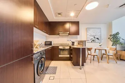 a kitchen with a washer and a table with chairs at Sleek DIFC Studio Perfect for Business & Leisure in Dubai