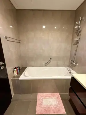 a bathroom with a white tub and a pink rug at Damac MERANO LUX 2 bedroom 3 baths in Dubai