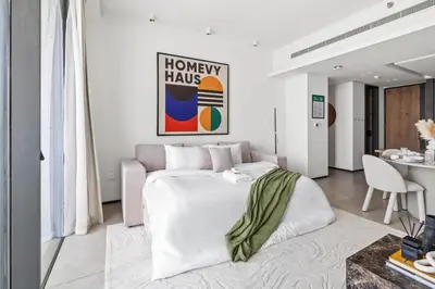 a bedroom with a large white bed and a table at Large 2BR with Work Desk, Pool, Gym and Kids Area in Dubai