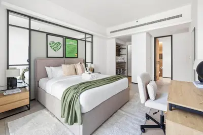 a bedroom with a bed and a desk and a chair at Large 2BR with Work Desk, Pool, Gym and Kids Area in Dubai
