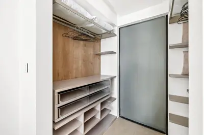 a walk in closet with white walls and a glass door at Large 2BR with Work Desk, Pool, Gym and Kids Area in Dubai