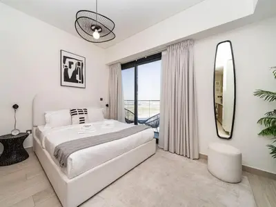 a white bedroom with a large bed and a large window at Bright and Sleek Azizi Studio Prime Meydan Location in Dubai