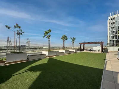 a park with a grassy area with benches and trees at Bright and Sleek Azizi Studio Prime Meydan Location in Dubai
