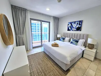 a bedroom with a large bed and a large window at SUNRISE HOMES - Spacious 1BR next to Marina Walk in Dubai