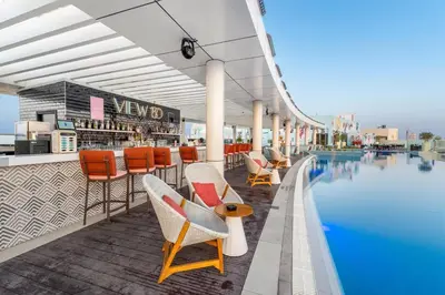 a view of the pool at a resort with chairs and a bar at Palm Jumeirah - Luxe Infinity Pool I Direct Beach Access in Dubai