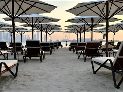 a group of chairs and umbrellas on the beach at Palm Jumeirah - Luxe Infinity Pool I Direct Beach Access in Dubai
