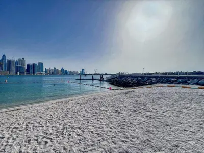 a sandy beach with a city in the background at Palm Jumeirah - Luxe Infinity Pool I Direct Beach Access in Dubai