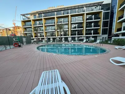 a building with a swimming pool in front of a building at Bright Studio Crystal Residence JVC in Dubai