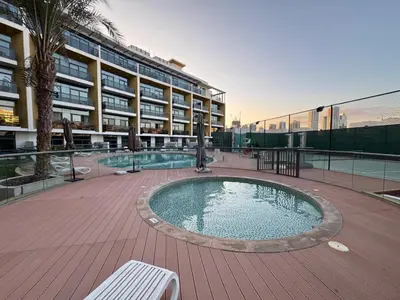 a large building with a swimming pool in front of a building at Bright Studio Crystal Residence JVC in Dubai