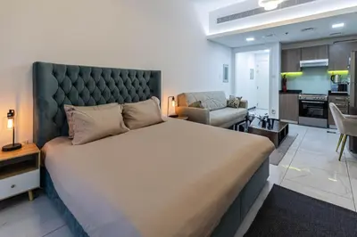 a bedroom with a large bed and a living room at Bright Studio Crystal Residence JVC in Dubai