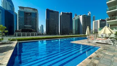 a swimming pool with a city skyline in the background at KeyRock Living - Chic Reva 1BR with Pool Access in Dubai