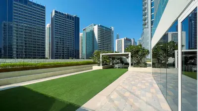 a green lawn in front of a city skyline at KeyRock Living - Chic Reva 1BR with Pool Access in Dubai