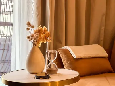 a table with a vase and a clock on it at KeyRock Living - Chic Reva 1BR with Pool Access in Dubai