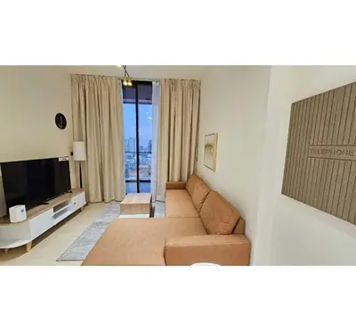 a living room with a couch and a television at Spacious 1BR Apartment in Binghatti Emerald JVC in Dubai