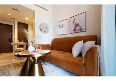 a living room with a brown couch and a table at Reva Residence - Luxe 1BR with Burj Khalifa View in Dubai