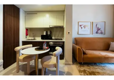 a kitchen and a living room with a table and a couch at Reva Residence - Luxe 1BR with Burj Khalifa View in Dubai