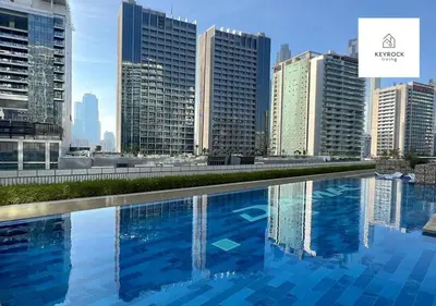 a large swimming pool in a city with tall buildings at Reva Residence - Luxe 1BR with Burj Khalifa View in Dubai