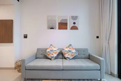 a blue couch in a living room with two pillows at Cozy 1 BR with gym & pool just 15min to Dubai Marina in Dubai
