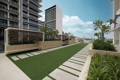 an apartment patio with a green lawn in front of a building at Cozy 1 BR with gym & pool just 15min to Dubai Marina in Dubai