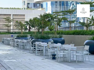 a row of white tables and chairs in front of a building at KeyRock Living - Zada 1BR with Pool & Gym Access in Dubai