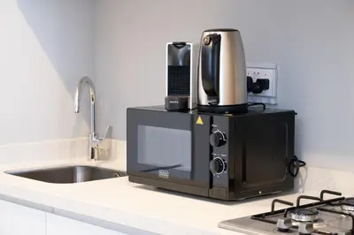 a microwave sitting on a counter next to a sink at KeyRock Living - Zada 1BR with Pool & Gym Access in Dubai