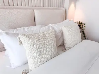 a pile of white pillows on a bed at Modern Chic Studio Apartment, Belgravia Heights 2, JVC Dubai in Dubai