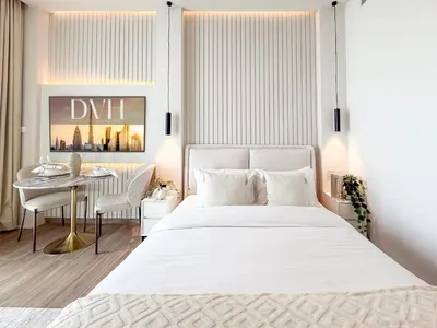 a bedroom with a white bed and a table at Modern Chic Studio Apartment, Belgravia Heights 2, JVC Dubai in Dubai