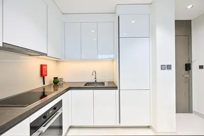 a kitchen with white cabinets and a sink at Stunning 1 Bdr Luxury District one in Dubai