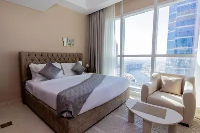 a bedroom with a bed and a chair and a large window at Court Tower in Dubai