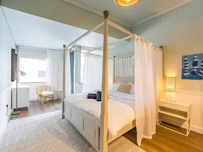 a bedroom with a canopy bed and a chair at Stylish 1-Bedroom with Panoramic Partial Sea View in Dubai