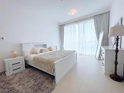 a white bedroom with a bed and a large window at Private Beach Access - Canal View in Dubai