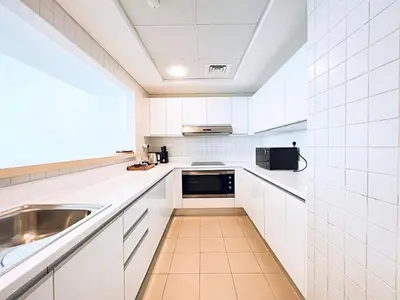 a white kitchen with a sink and a microwave at Private Beach Access - Canal View in Dubai
