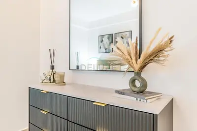 a dresser with a mirror and a vase on it at City View 2BR Just Steps from the Mall, Roxana Residence B, Jumeirah Village Circle by Deluxe Holiday Homes in Dubai