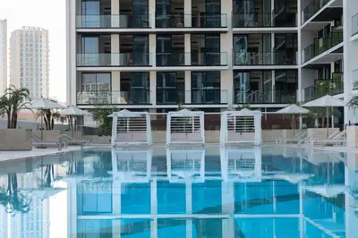 a swimming pool with chairs and a building at Jvc 1br Oasis Serene Interiors Pool & Parking in Dubai