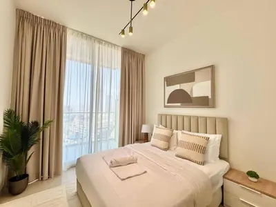 a bedroom with a bed and a large window at Jvc 1br Oasis Serene Interiors Pool & Parking in Dubai