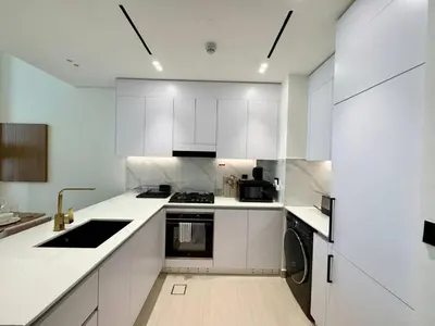 a white kitchen with white cabinets and a sink at Jvc 1br Oasis Serene Interiors Pool & Parking in Dubai