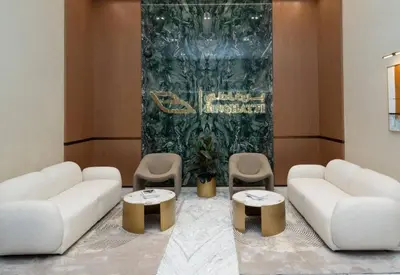a living room with two white couches and two tables and chairs at Jvc 1br Oasis Serene Interiors Pool & Parking in Dubai